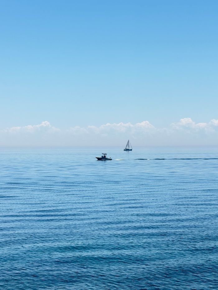 A calm ocean view under a clear blue sky featuring boats on a serene day.